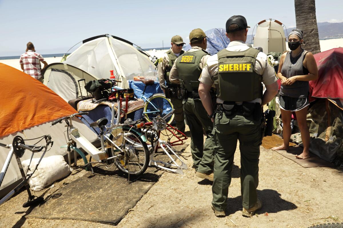 L.A. County Sheriff Deputies talk with Amanda Rivers, 34, who lives in a homeless encampment along Ocean Front Walk 