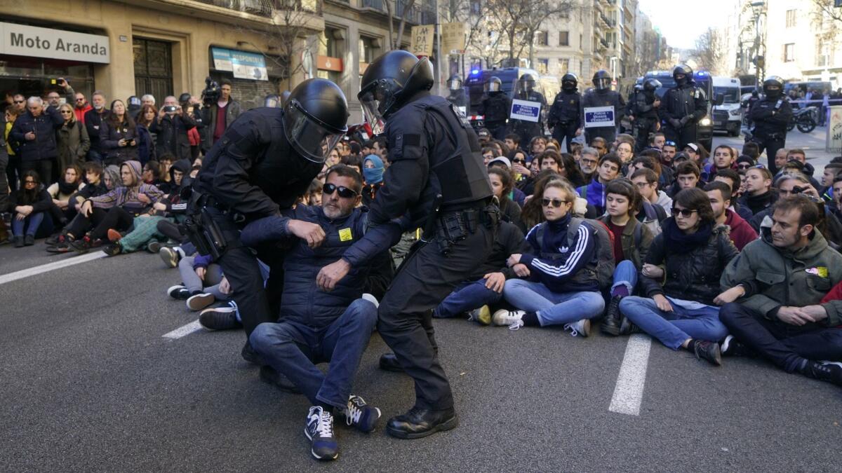Demonstrators calling for Catalan independence are removed by police officers during a sit-down protest outside the Barcelona office of the state prosecutor on Feb. 12.