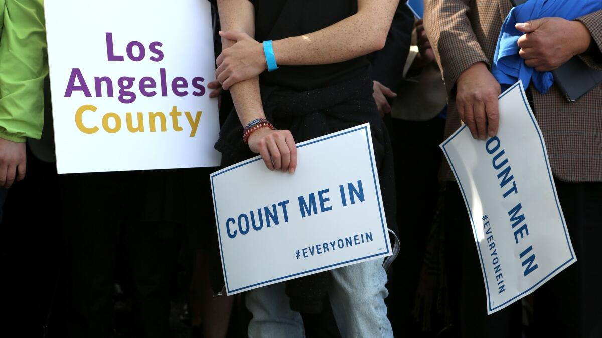 Members of the crowd hold signs as they listen to speakers during the launch of "Everyone In," a campaign to bring people throughout L.A. County together around the goal of ending homelessness.
