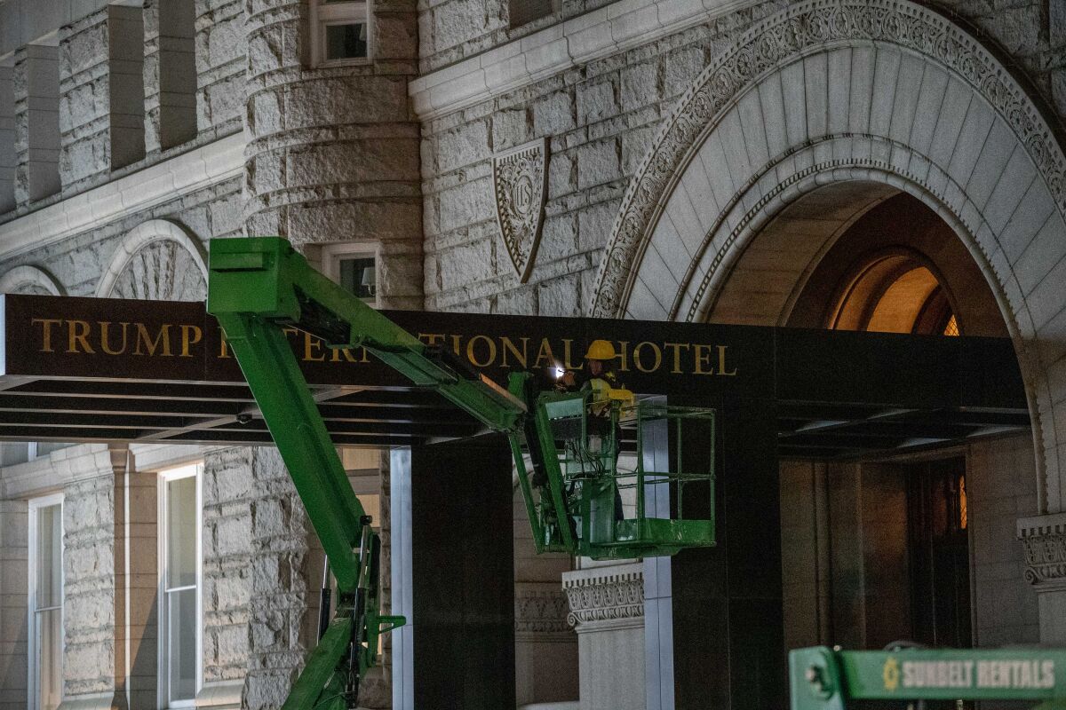 A worker removes the signage for the Trump International Hotel Wednesday, May 11, 2022, in Washington. The lease to the Washington hotel run by Donald Trump's family company while he was president, has been sold by his family company to a Miami-based investor fund. (AP Photo/Gemunu Amarasinghe)