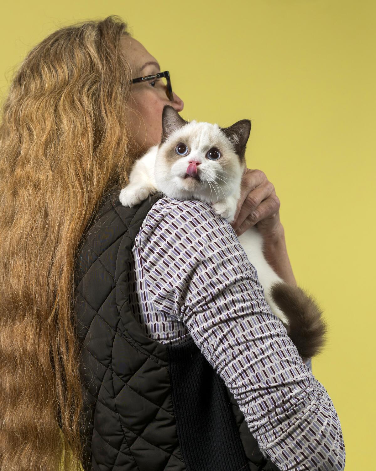 Honey Bunny, a Minuet cat, looks over Karolyn McCall's shoulder with its tongue touching its nose.