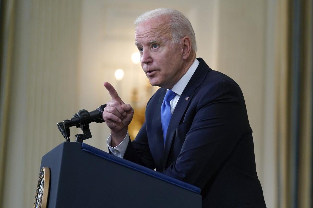 President Biden speaks at a podium and points his finger 