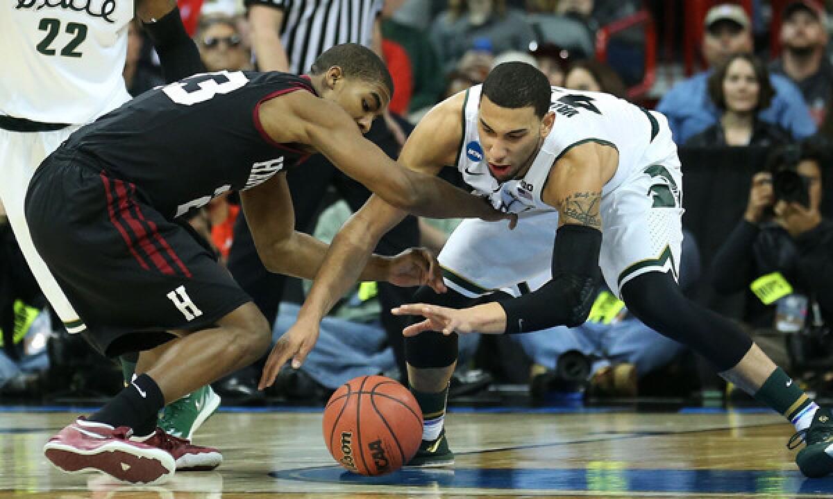 Harvard's Wesley Saunders, left, and Michigan State's Denzel Valentine battle for a loose ball during the second half of the Spartans' 80-73 win in the third round of the NCAA tournament Saturday.