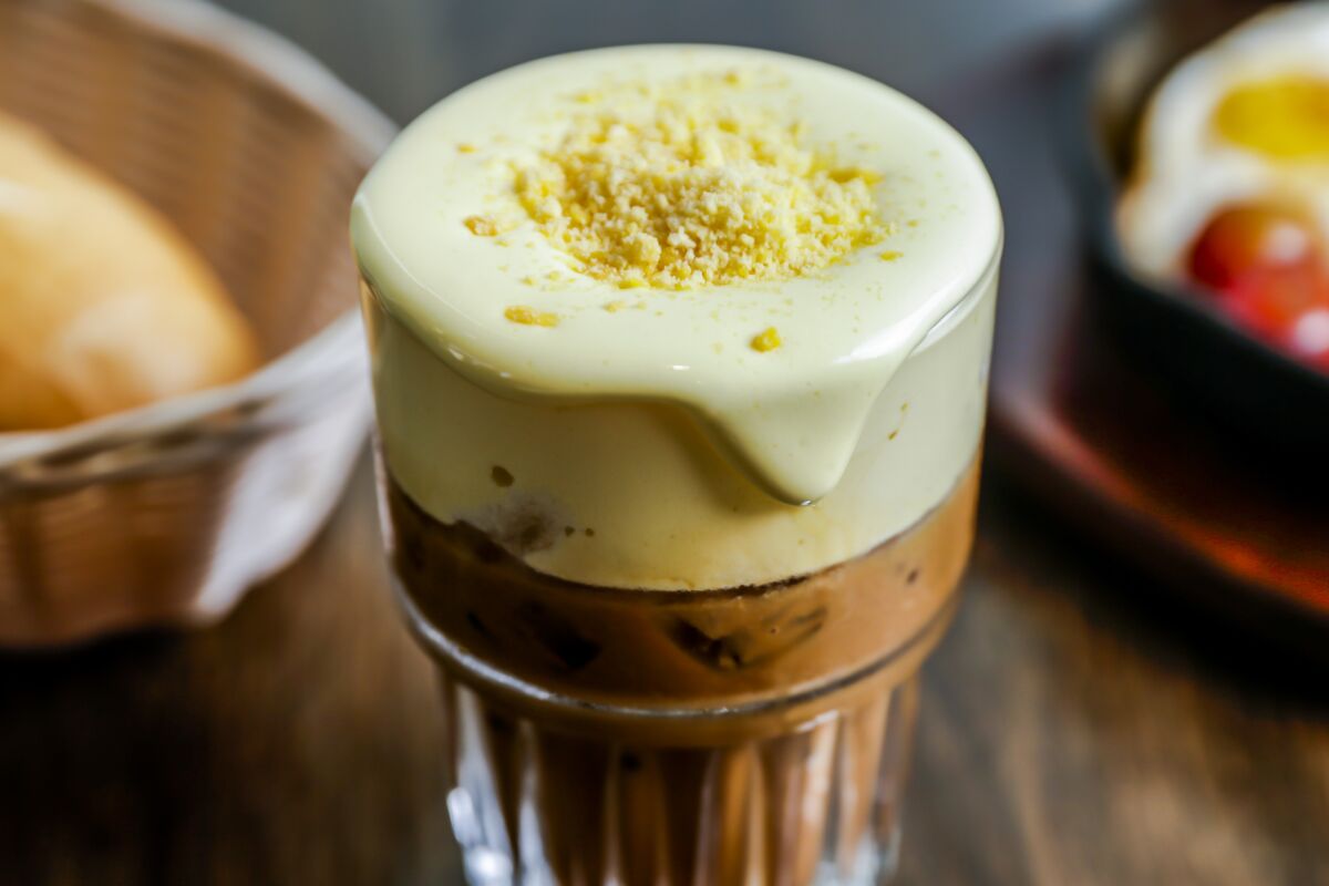 coffee drink with foam topping and grated salted egg yolk in a clear glass 