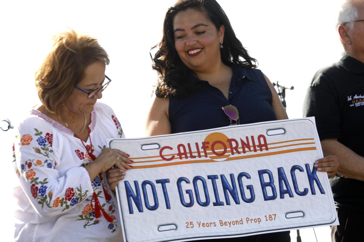 California State Senator Maria Elena Durazo, left, and California Assembly Member Wendy Carrillo hold a sign together after speaking to a crowd.