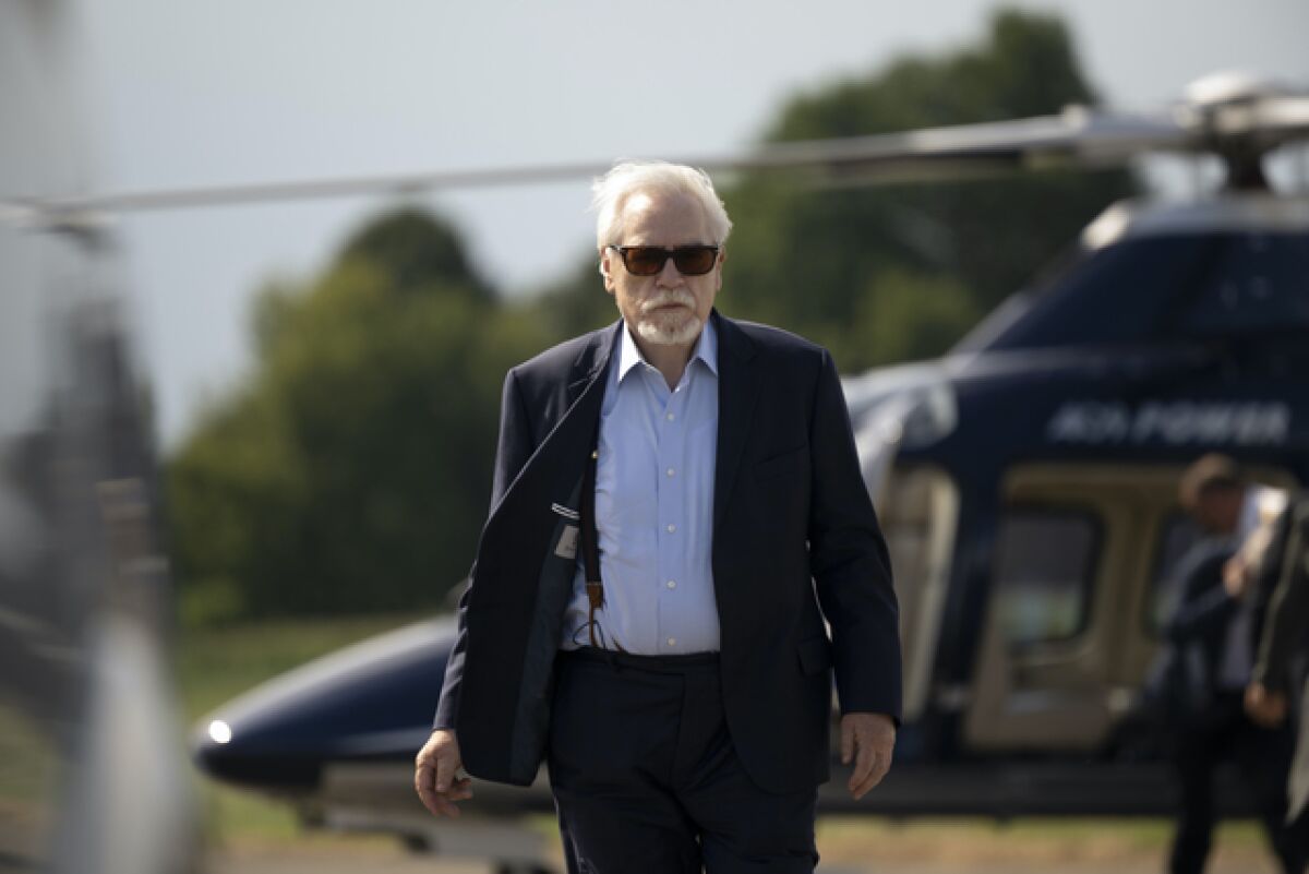 Brian Cox, as Logan Roy, is seen disembarking from a helicopter, wearing sunglasses and looking powerful.