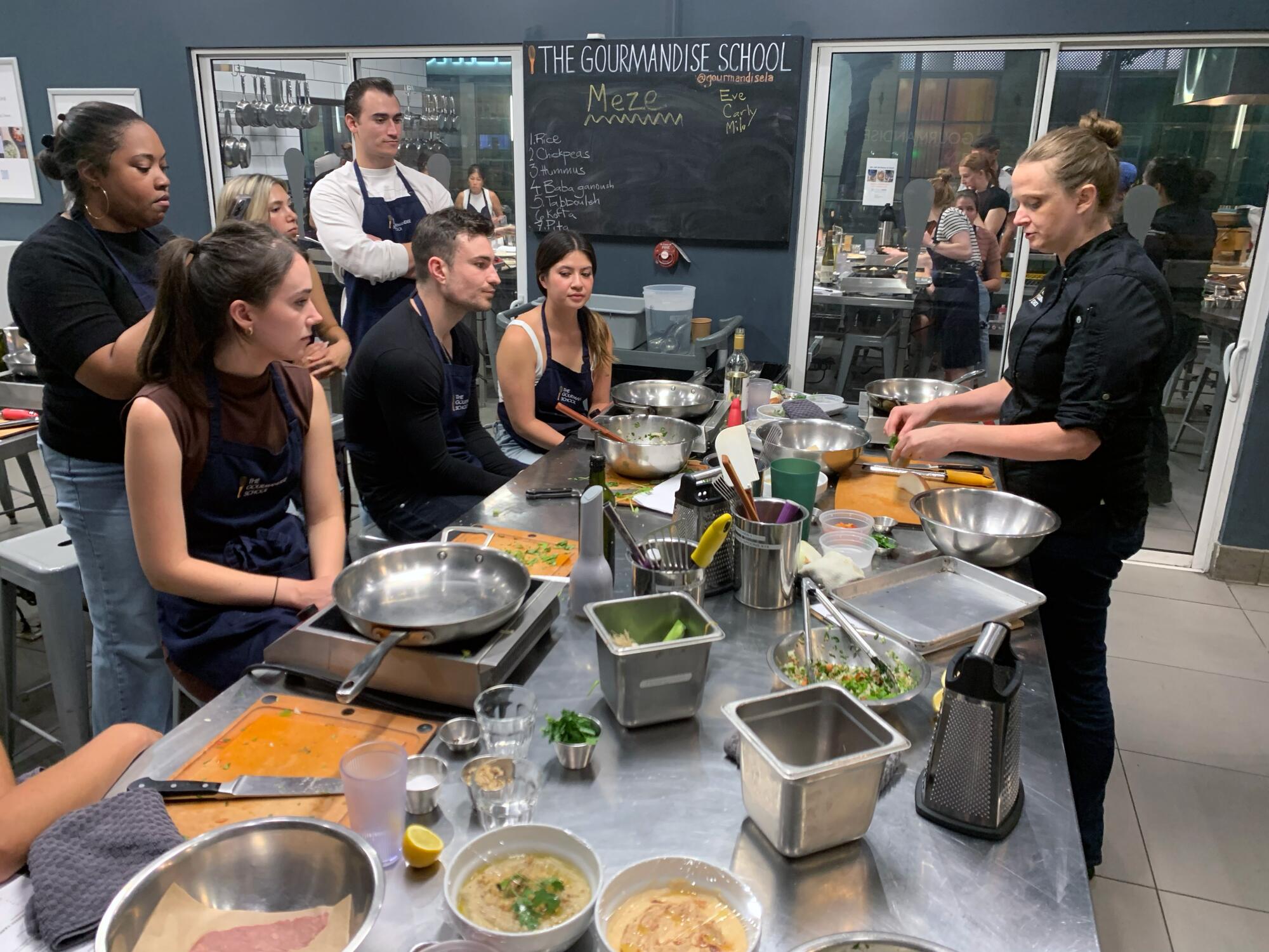 People taking a cooking class watch the instructor. 