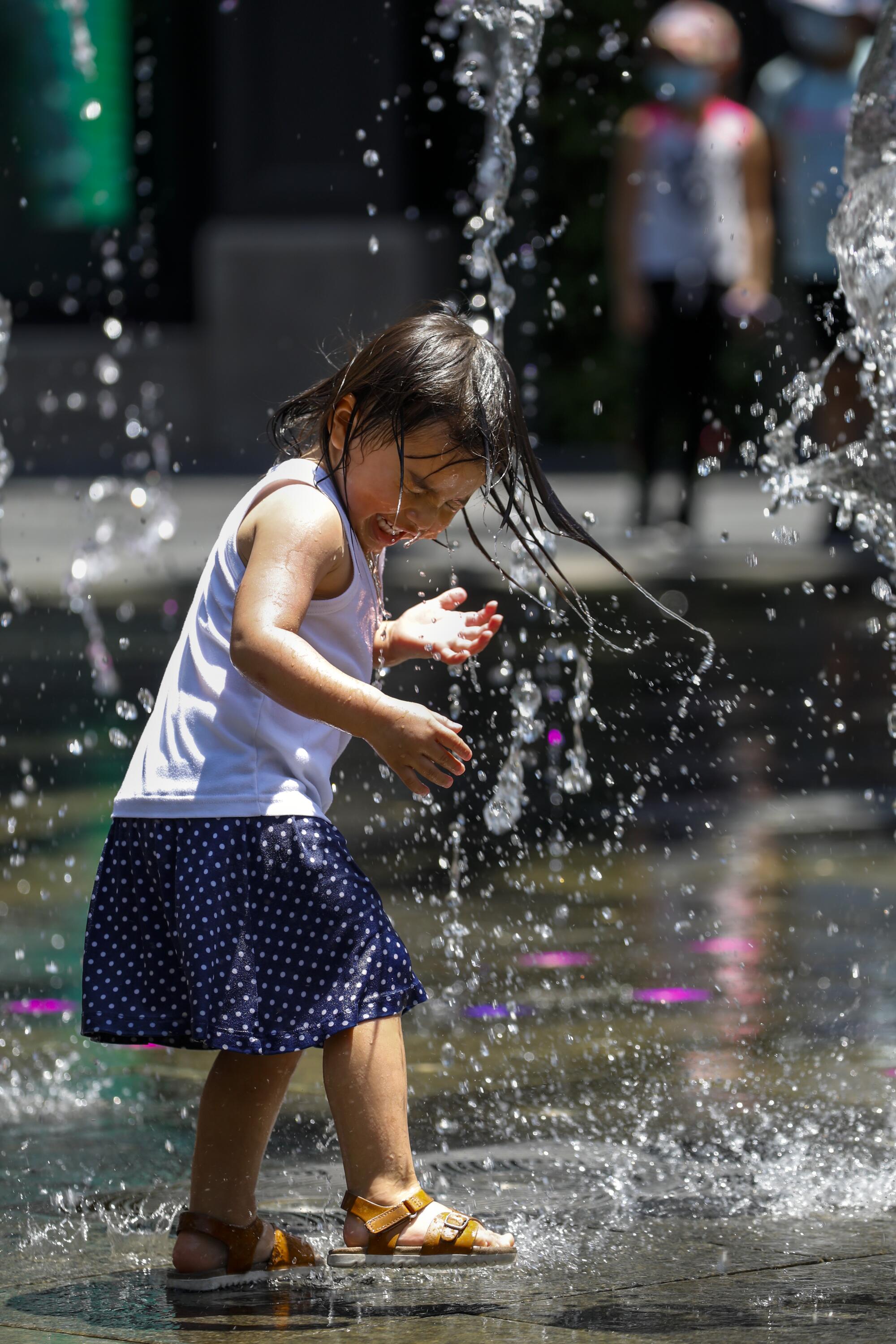 A small child plays in a public water fountain