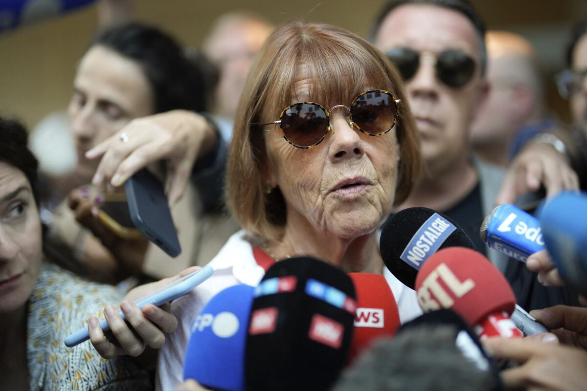 A woman speaks as reporters hold up microphones.