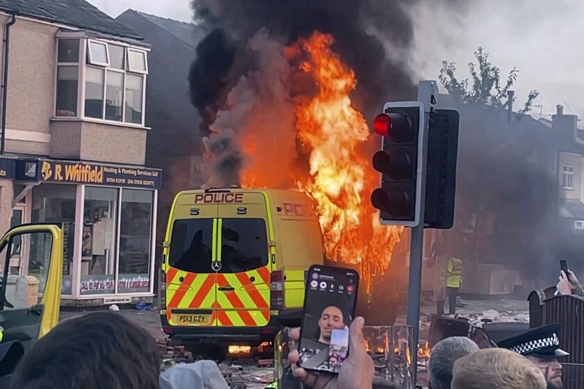 Una camioneta policial arde mientras una multitud choca con al policía el martes 30 de julio de 2024 en Southport, en el noroeste de Inglaterra, donde tres niñas murieron tras ser apuñaladas el día anterior. (Richard McCarthy/PA via AP)