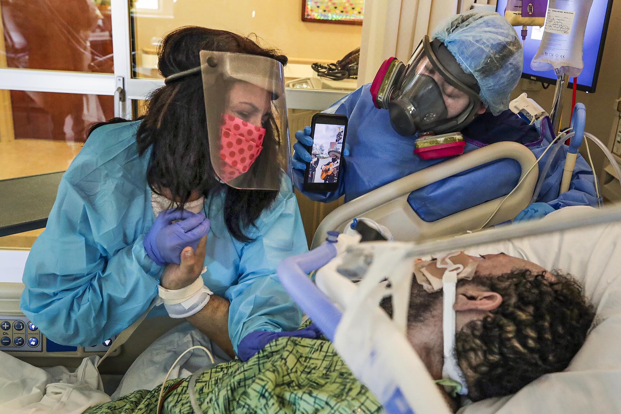 Patty Trejo holds the hand of her husband, Joseph Trejo, who is on a ventilator.