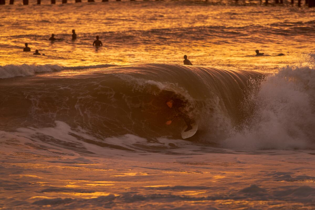 A tube-like wave surrounds a surfer at sunset.