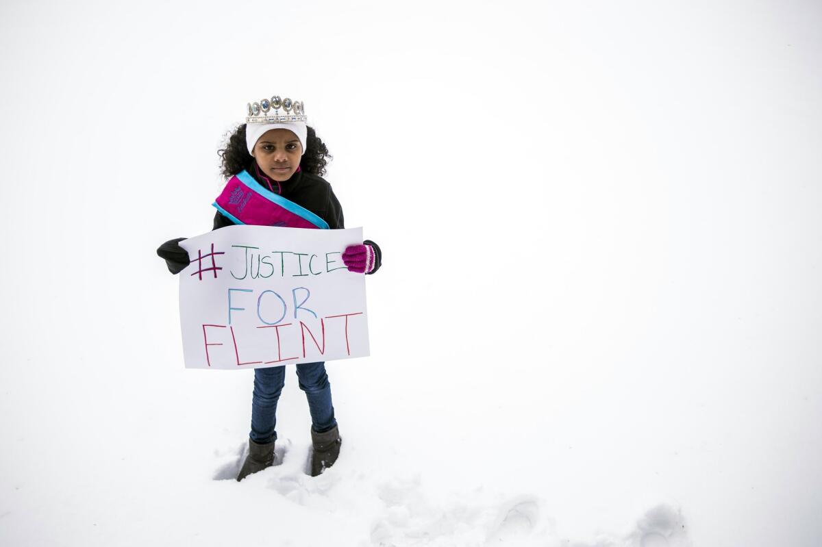 Mari Copeny, 8, of Flint, Mich., stands with a protest sign during a #Justice4Flint rally at Wilson Park on University of Michigan-Flint's campus in Flint, Mich.