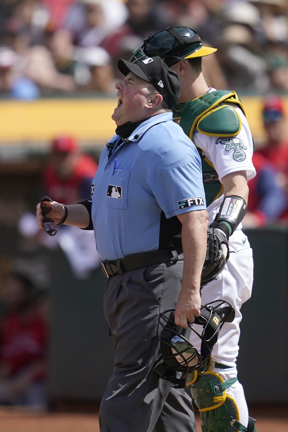 Home plate umpire Marty Foster, left, reacts after being hit by a ball in front of Oakland Athletics catcher Sean Murphy, right, during the seventh inning of a baseball game against the Los Angeles Angels in Oakland, Calif., Sunday, May 15, 2022. (AP Photo/Jeff Chiu)