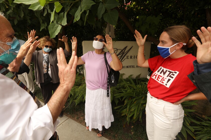 SANTA MONICA, CA - AUGUST 26, 2020 - - Rabbi Neil Comess-Daniels, left, prays over Margarita Santos, 62, center, in pink top, as others join in at the end of the demonstration in support of Santos in front of Le Merigot Hotel in Santa Monica on August 26, 2020. Santos was fired from her job as a housekeeper at the hotel after getting COVID-19. Members of Unite Here Local 11, Santa Monica politicians and religious leaders demonstrated in front of the hotel to try and get Santos her job back. "I believe I contracted COVID at work," Santos said. (Genaro Molina / Los Angeles Times)