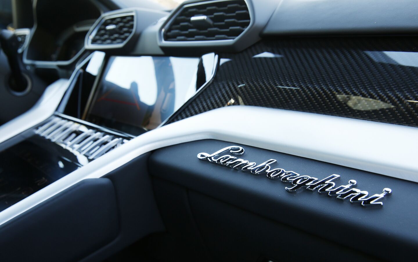 The Urus' interior with "Lamborghini" in silver script above the glove compartment.