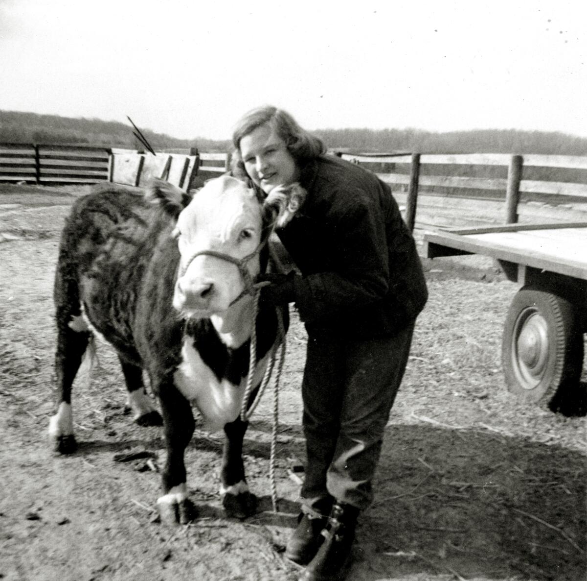 A black-and-white photo of a girl with short hair posing with her steer.