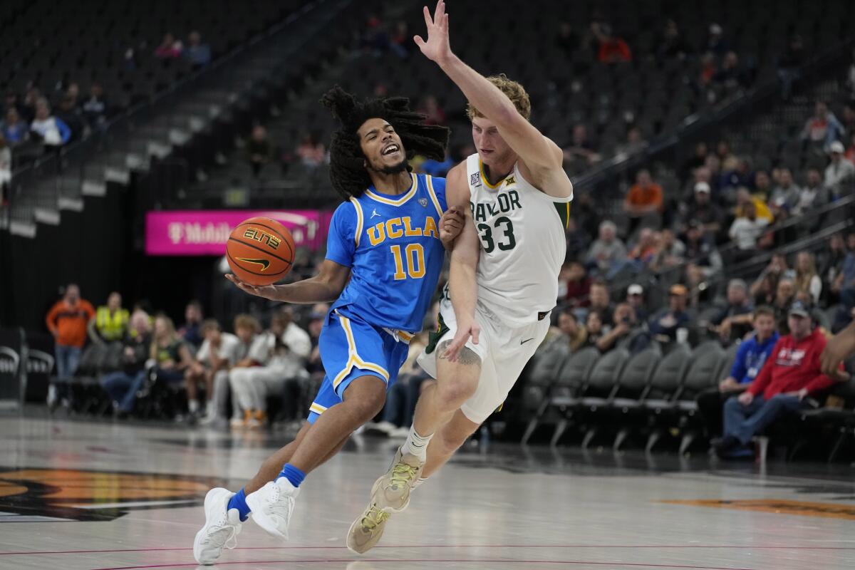 UCLA guard Tyger Campbell, left, drives into Baylor forward Caleb Lohner during the first half Sunday.