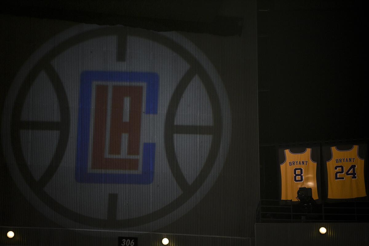 The retired jerseys of late Los Angeles Lakers' Kobe Bryant hangs above the arena next to a projected logo of the Los Angeles Clippers prior to an NBA basketball game against the Sacramento Kings in Los Angeles, Thursday, Jan. 30, 2020. (AP Photo/Kelvin Kuo)