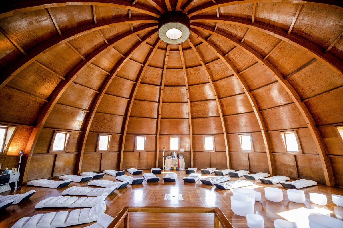 The wood-beamed interior of the Integratron dome, with white cots in a semicircle.