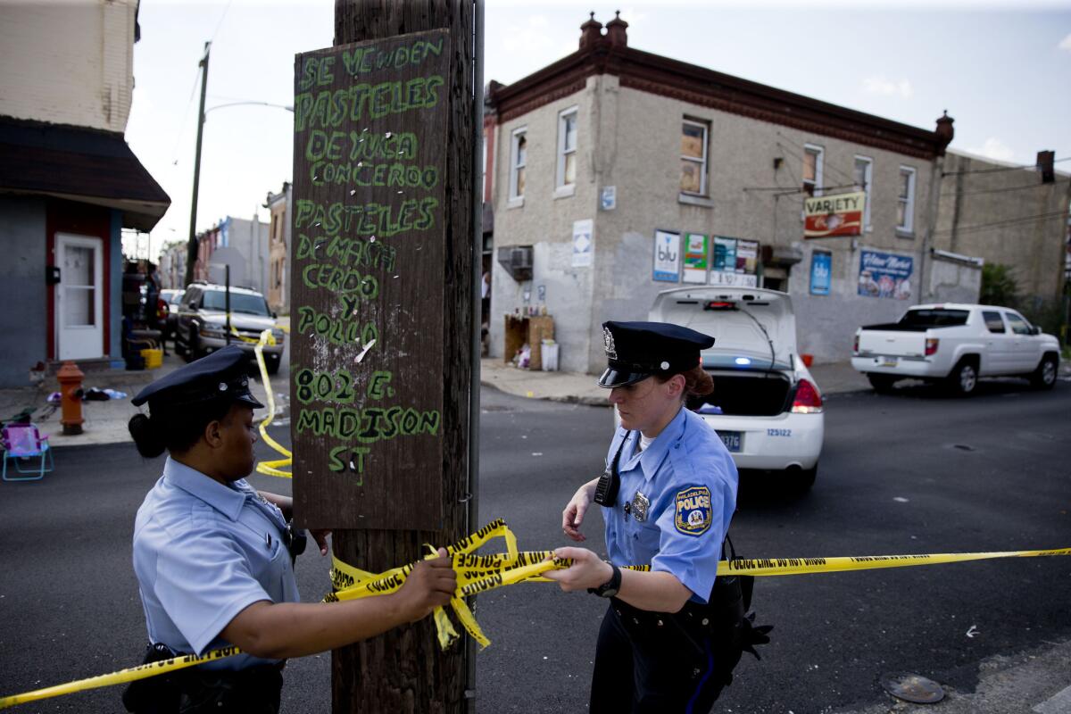 Policías demarcan con cinta amarilla un lugar en Filadelfia después de que varias personas resultaron heridas a causa de un ataque con escopeta, el lunes 22 de junio de 2015. El incidente ocurrido en el barrio de Kensington es el segundo de su tipo desde el sábado sin que haya detenidos, según la policía. (AP Foto/Matt Rourke)