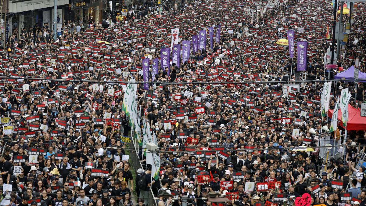 Thousands of protesters shouting slogans and carrying signs fill the streets of Hong Kong on Sunday.