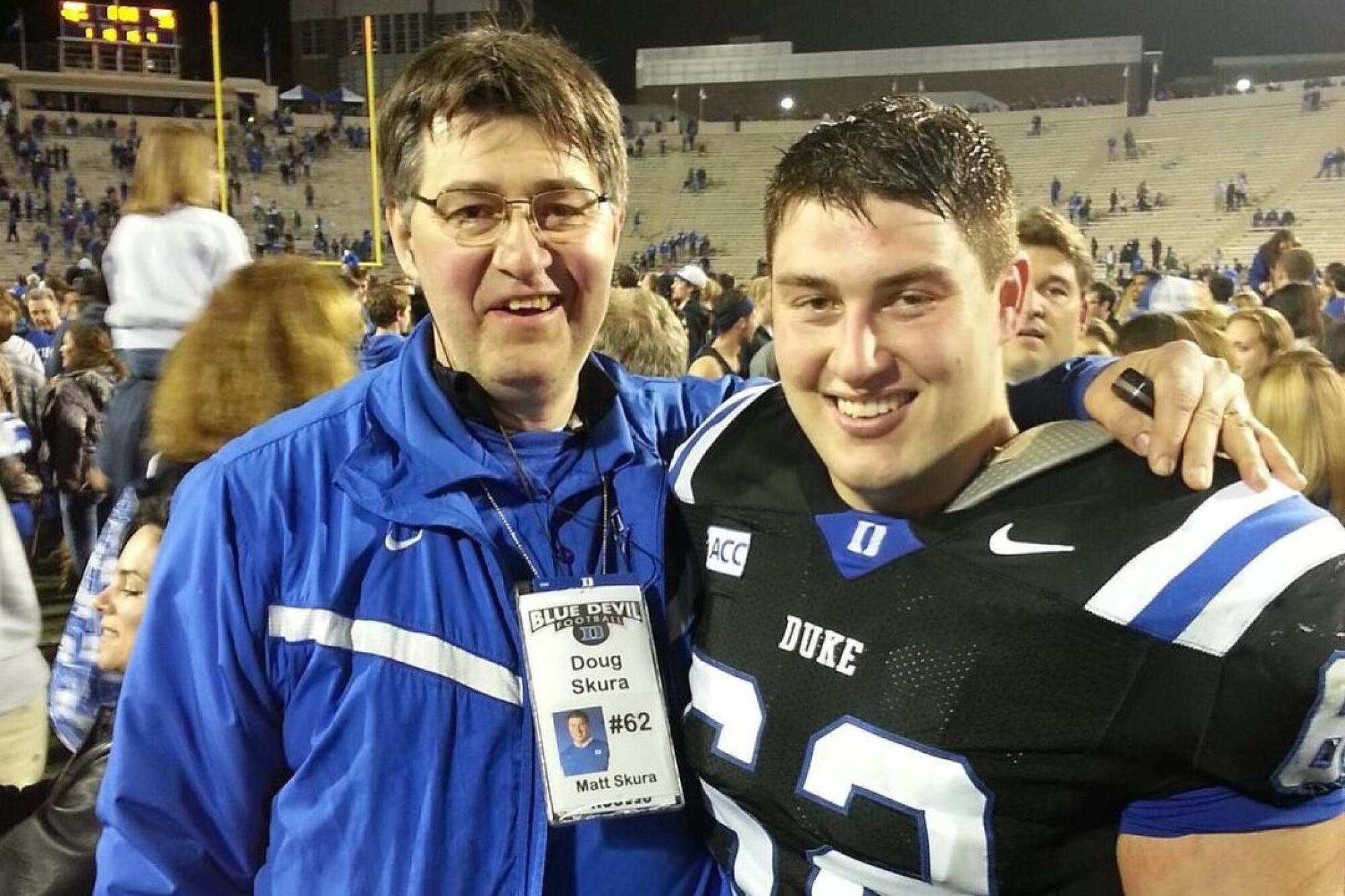 Doug Skura embraces his son, Matt, after a Duke football game. Matt is wearing his Duke football uniform.