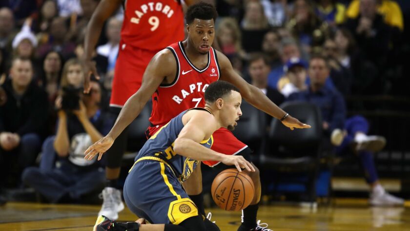 Golden State Warriors' Stephen Curry (30) dribbles on his knees while being guarded by Toronto Raptors' Kyle Lowry (7) on Dec. 12, 2018 in Oakland.