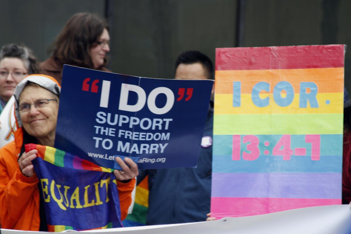 Lin Davis of Juneau, Alaska, second from left, holds signs supporting gay marriage Friday outside the federal courthouse in Anchorage.