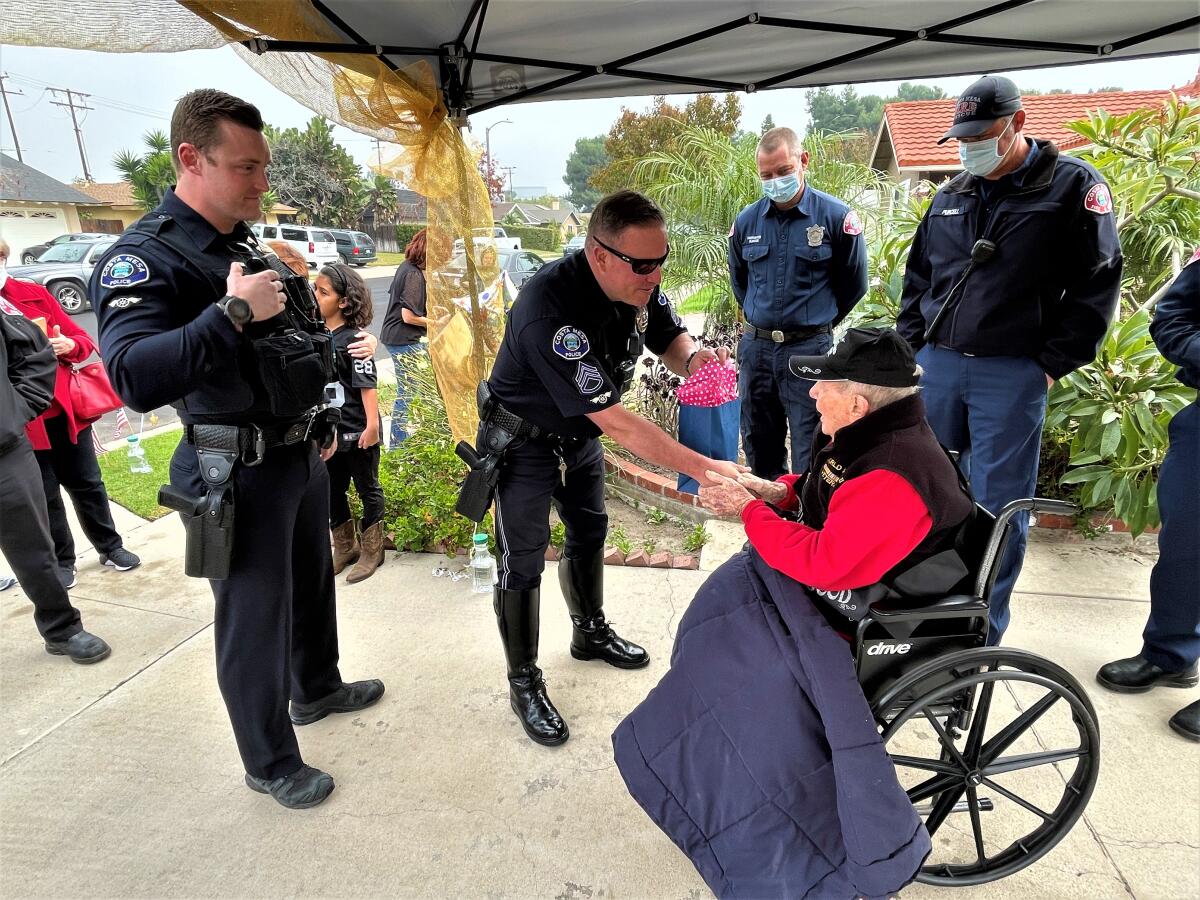 Costa Mesa police officers give centenarian Merl "Bus" Cornelius a gift.