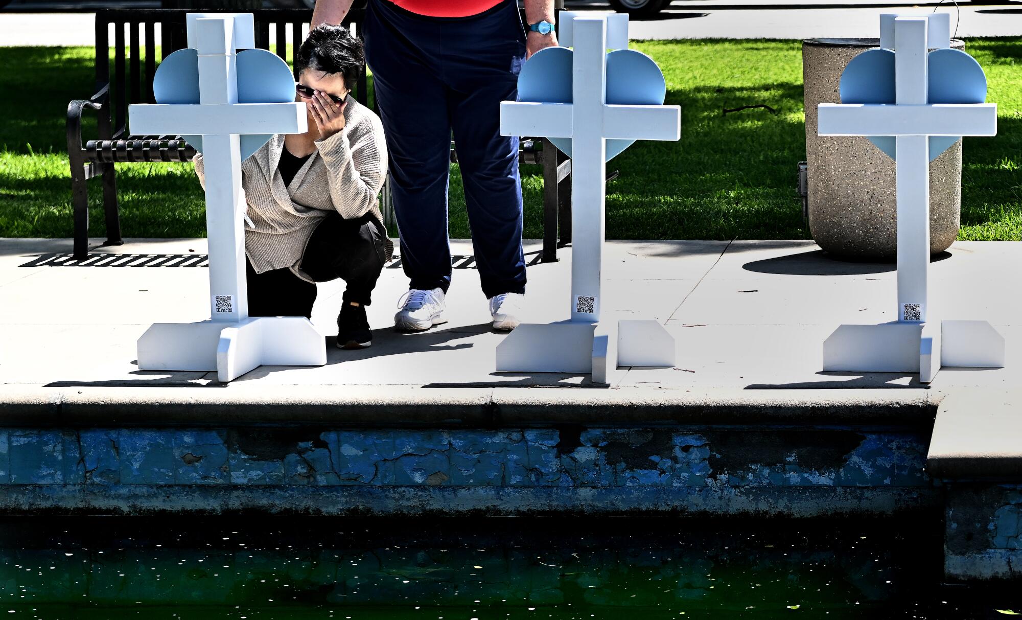 A Robb Elementary school employee kneels at a memorial for the victims in Uvalde, Texas, on Thursday.