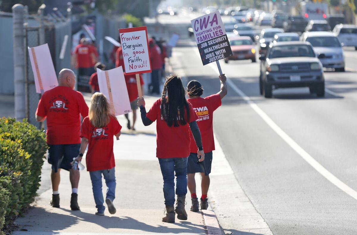 Local employees unionized by CWA march down Slater Avenue in front of the Huntington Beach Frontier office on Thursday.