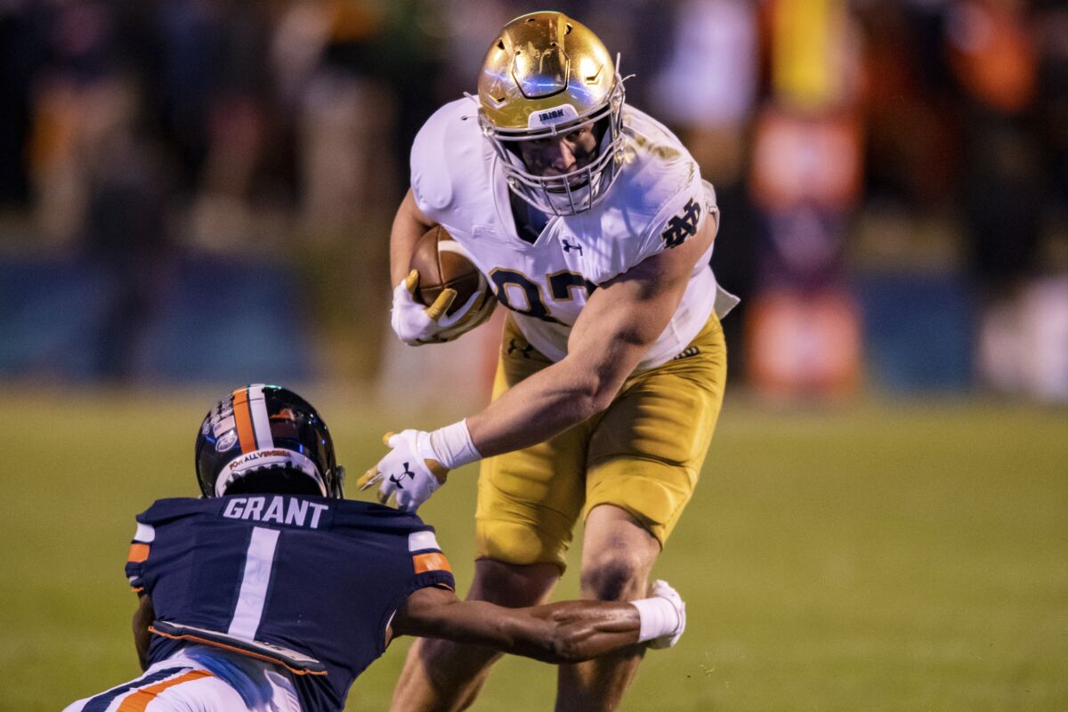 Notre Dame tight end Michael Mayer (87) avoids Virginia cornerback Nick Grant (1) during the first half of an NCAA college football game on Saturday, Nov. 13, 2021, in Charlottesville, Va. (AP Photo/Mike Caudill)