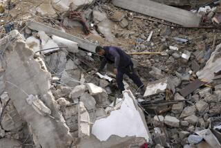 A Palestinian looks at the destruction after an Israeli strike at a residential building in Deir al Balah, Gaza Strip, Sunday, Jan. 14, 2024. (AP Photo/Adel Hana)