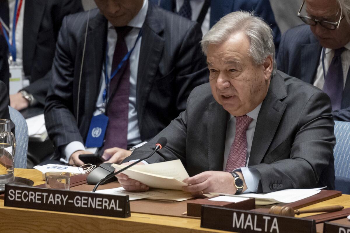 United Nations Secretary-General António Guterres holding a sheaf of papers while speaking at a table