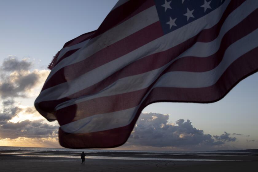 A man in a vintage US WWII uniform walks at sunrise prior to a D-Day 76th anniversary ceremony in Saint Laurent sur Mer, Normandy, France, Saturday, June 6, 2020. Due to coronavirus measures many ceremonies and memorials have been cancelled in the region with the exception of very small gatherings. (AP Photo/Virginia Mayo)