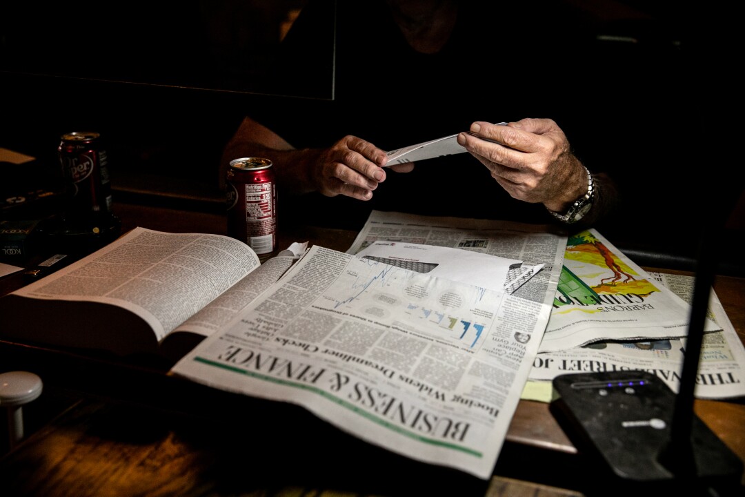 Lutzius sorts through bills while sitting alone at the bar on Tuesday.
