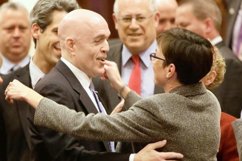 State Rep. Greg Harris, left, a gay Democrat from Chicago, is congratulated by lawmakers as a same-sex marriage bill passes the House in Springfield, Ill.