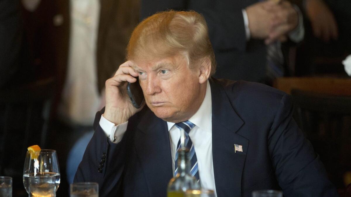 Donald Trump usa un teléfono celular mientras hace campaña para presidente en North Charleston, S.C., el 18 de febrero de 2016.