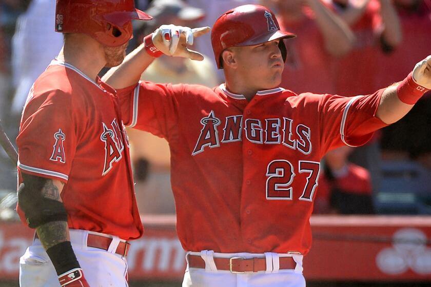 Angels center fielder Mike Trout (27) does a bow-and-arrow flex toward teammate Albert Pujols, who doubled home Trout with the tying run against the Mariners in the ninth inning Sunday afternoon.