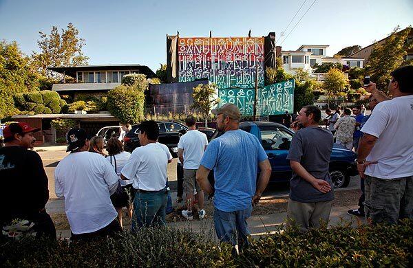 Neighbors and friends of property owner Adam Corlin get a look from across the street after the unveiling of a gigantic artwork. See full story