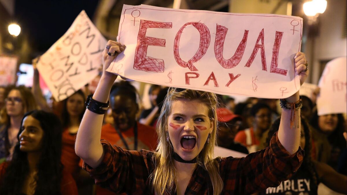 An International Women's Day marcher lets her support of equal pay be known.