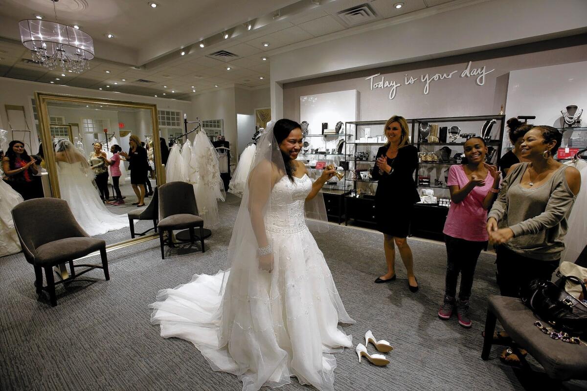 Bride-to-be Tomi Dorsey tries on a wedding gown at David's Bridal new, more upscale Los Angeles location, assisted by store manager Sonni Sandersht. Erin Bradley and Tomi's sister Ganell Dorsey, right, enjoy the scene.