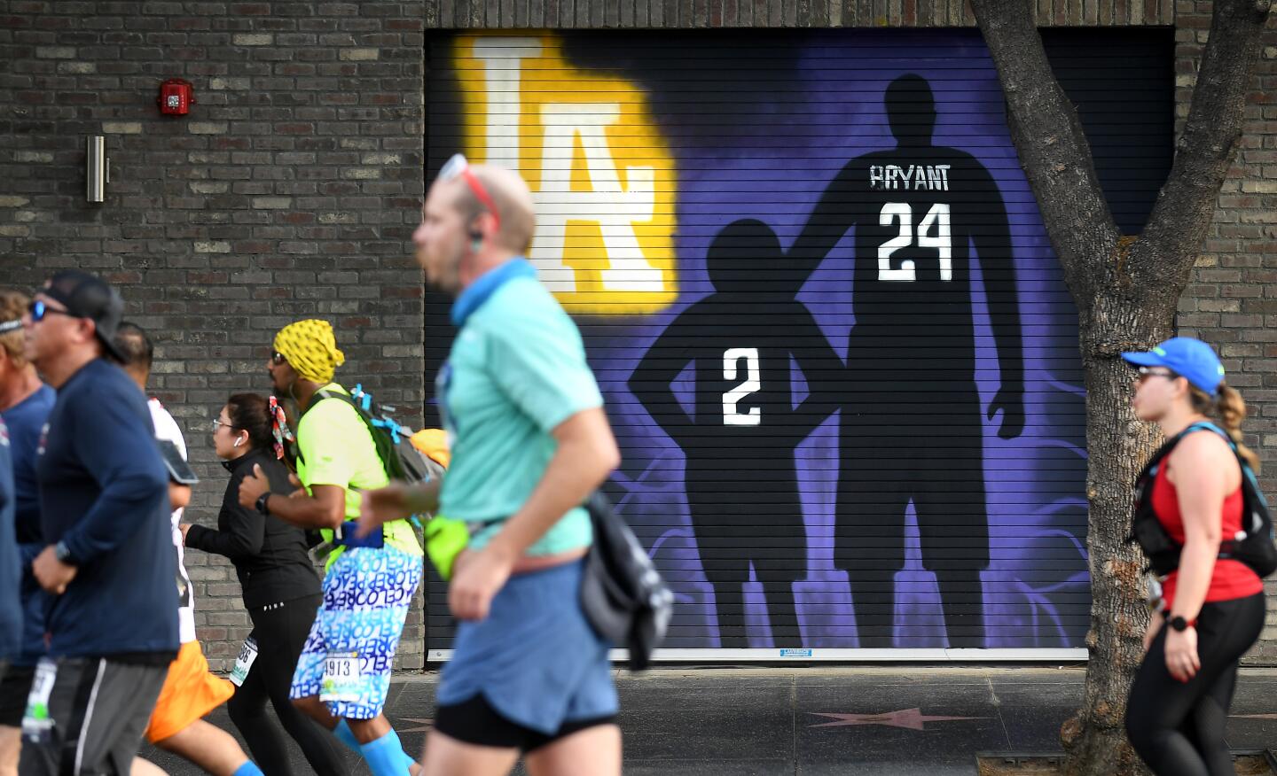 Competitors run by a mural of Kobe Bryant and his daughter Gianna along Hollywood Blvd. in Hollywood Sunday during L.A. Marathon.
