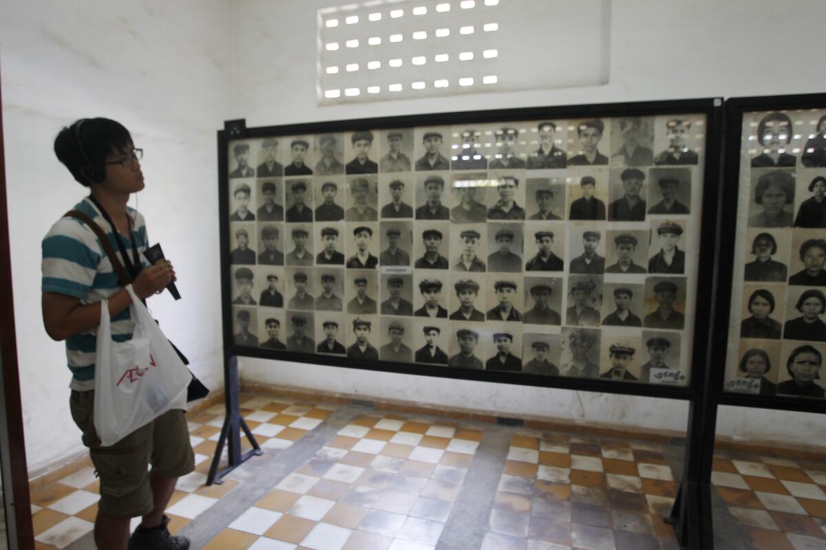 A tourist views portraits of victims executed by the Khmer Rouge regime at the Tuol Sleng Genocide Museum in Phnom Penh, Cambodia on Feb. 5, 2018. Cambodians on Monday, April 12, 2021, continued to condemn an Irish photo restorer for altering photographs of victims of their country’s 1970s genocide to show them smiling, saying his decision and that of an international media group to publish them showed horrible judgement.(AP Photo/Heng Sinith)