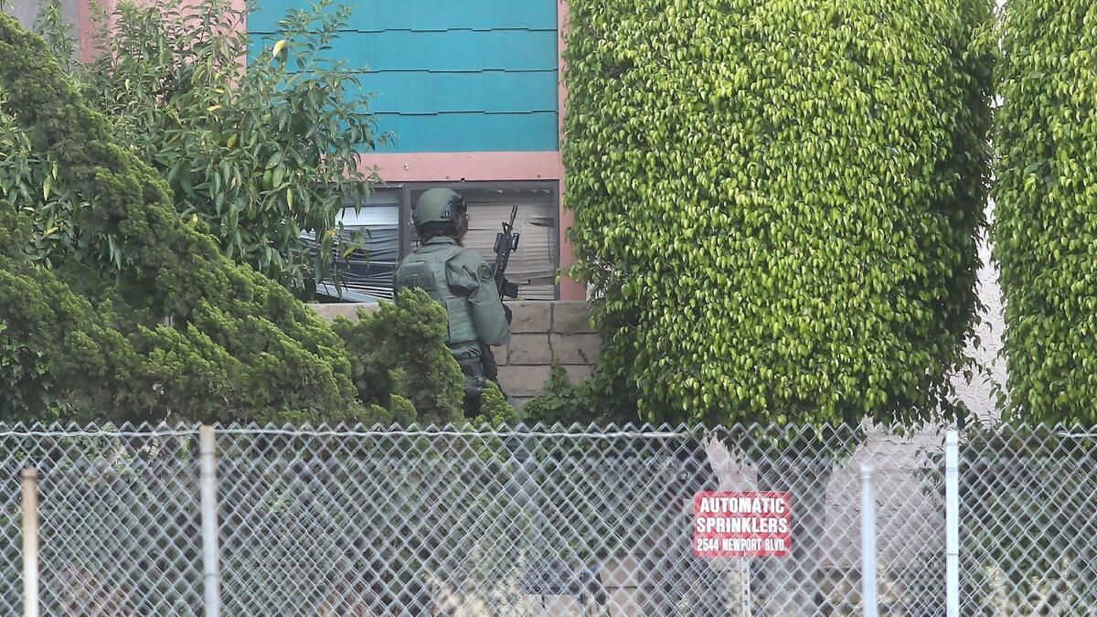 A SWAT team member watches a window at the Regency Inn in Costa Mesa, where a man barricaded himself in a room Tuesday.
