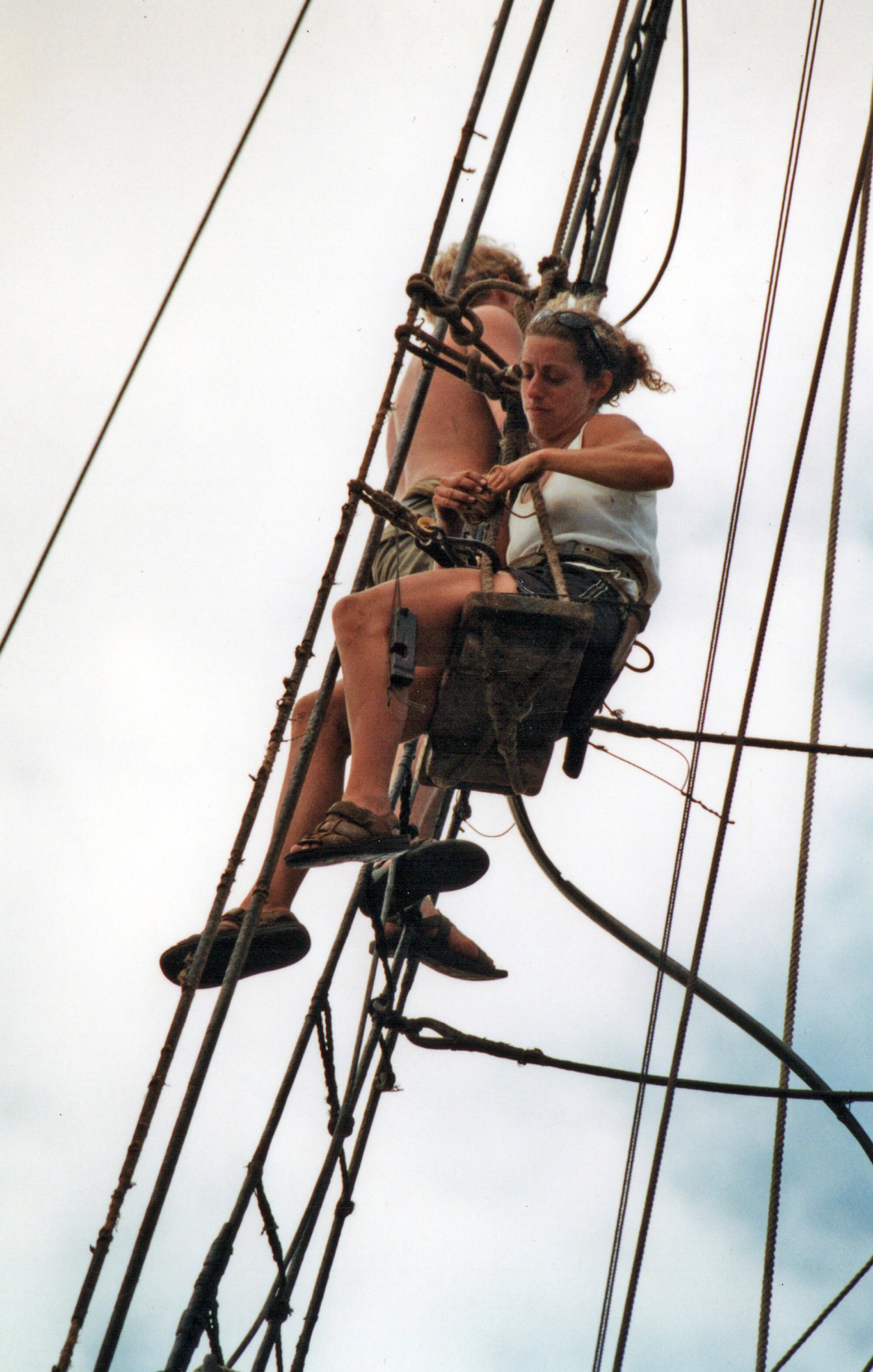Crew members high in the ship's rigging.