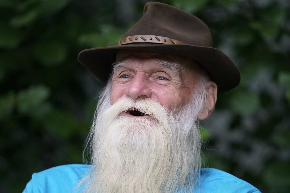 FILE — David Lidstone, 81, known to locals as "River Dave," speaks with reporters during an interview with The Associated Press Tuesday, Aug. 10, 2021, in Boscawen, N.H. A warrant has been issued for the arrest of the former hermit in New Hampshire who is charged with trespassing on the wooded property he made his home for 27 years after he didn't show up for his arraignment. A prosecutor said Monday, March 7, 2022, the state of New Hampshire has had no contact with 81-year-old David Lidstone on the misdemeanor charge.2 (AP Photo/Steven Senne, File)