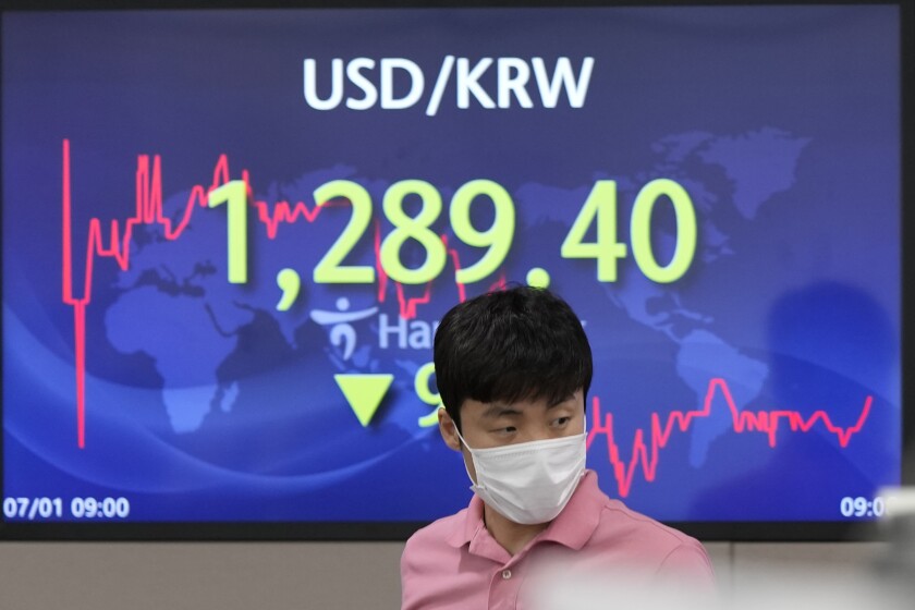 A currency trader walks by the screen showing the foreign exchange rate between U.S. dollar and South Korean won at a foreign exchange dealing room in Seoul, South Korea, Friday, July 1, 2022. Asian benchmarks were mostly lower on Friday, echoing a decline on Wall Street, after a quarterly report by Japan’s central bank rekindled worries about the world’s third largest economy. (AP Photo/Lee Jin-man)