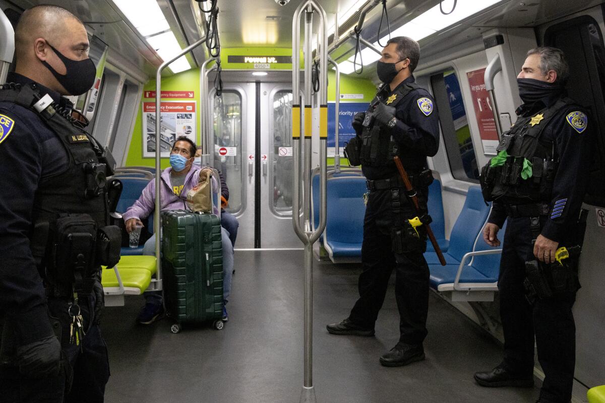 Police officers and riders wear masks on a BART train in San Francisco on April 28. 